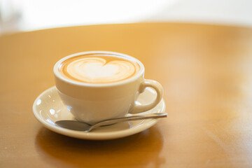 Top  of hot latte coffee with latte art in a white cup on wooden table
