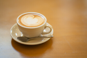 Top  of hot latte coffee with latte art in a white cup on wooden table