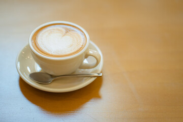 Top  of hot latte coffee with latte art in a white cup on wooden table