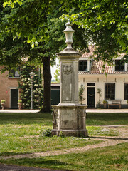 Obraz premium Historic village pump with ornamental column on the green in Nisse, Zeeland
