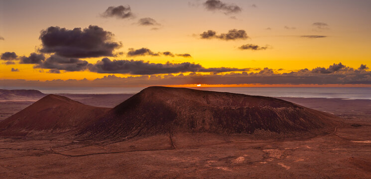 Spectacular sun set image over Volcan Calderon Hondo volcanic crater silhouetted against the setting sun and skyscape near Corralejo, Fuerteventura, Canary Islands, Spain - Powered by Adobe
