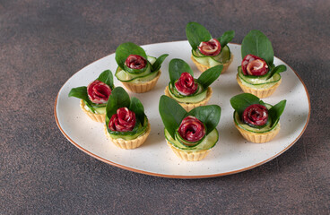 Tartlets in shape of roses with sausage, cucumber and spinach, festive snack