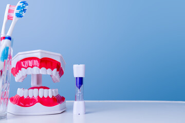 Dental hygiene tools with toothbrush, model dentures, and timer on blue background