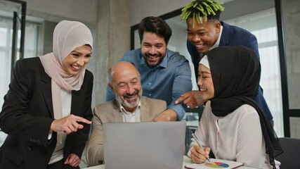 Multiethnic team of businesspeople collaborating and smiling while reviewing project data on laptop, pointing their fingers toward the screen while sharing ideas - Powered by Adobe
