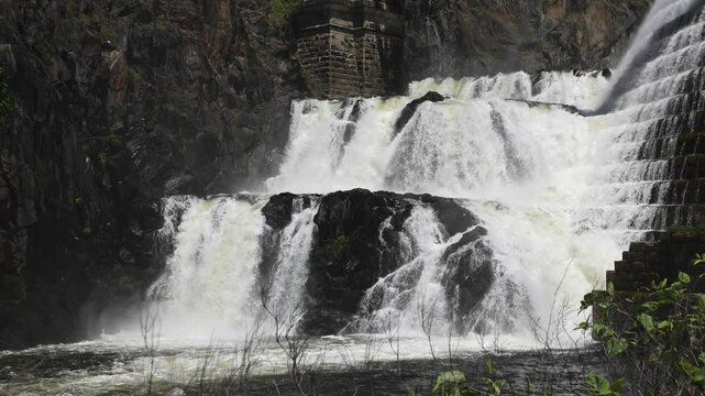 water cascading down waterfall at croton dam (man made and natural drinking water reservoir) westchester new york landmark with old bridge (tourism travel hiking destination) nature landscape