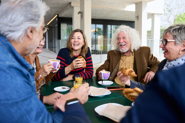 Happy senior people having breakfast sitting at cafe bar. Group of older friends having snack in terrace restaurant chatting merrily together. Food and beverage life style on maturity concept