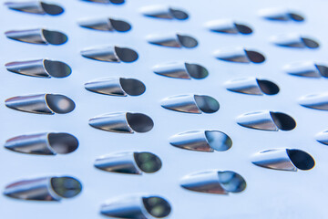 Abstract. Close-up of metal grater with oval-shaped blades.