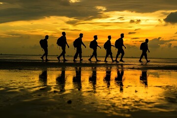 Silhouette of hikers walking along a beach at sunset