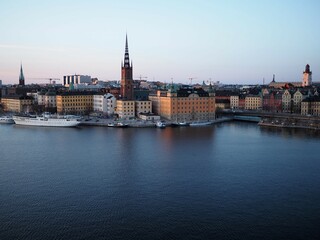 Evening View of Riddarholmen Island in Stockholm, Sweden. Riddarholmen Church, scandinavian architecture. Black roofs of the old town and ships on the embankment.
