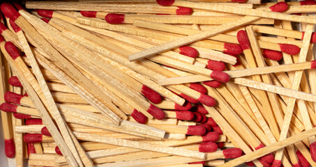 Pile of wooden matches with red tips scattered randomly inside a box showing natural texture and...