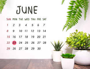 Wooden block calendar with date June 23 on white concrete background.