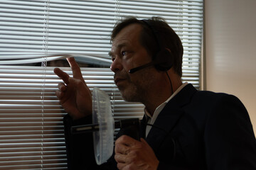 Reconnaissance and eavesdropping. A man holds a parabolic microphone device by the window,...