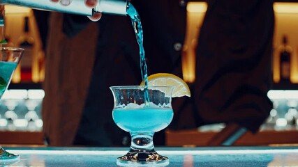A close-up video shot of a bartender mixing cocktails, showcasing vibrant drinks and a sleek, modern bar setting with a focus on hand movements.