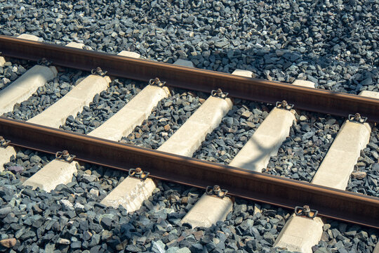 This image, reflecting a transportation concept, shows a close-up of modern railroad tracks with concrete sleepers embedded in dark ballast.