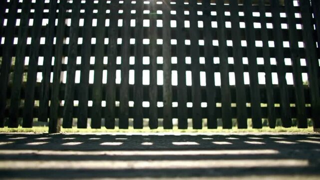 Sunlight Peeking Through The Wooden Fence Of A Rustic Farm With Strong Shadows