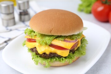Tasty cheeseburger with lettuce and tomatoes on white table, closeup