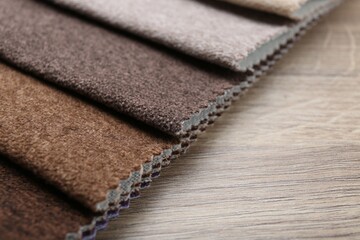 Samples of different fabrics on wooden table, closeup