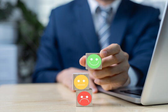 Customer satisfaction survey concept. Businessman holding wooden block with smile icon from satisfaction, business service experience evaluation, customer service, business credibility.