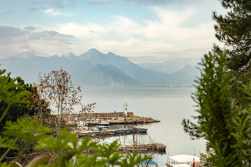 Naklejka premium Serene harbor with distant mountains and lighthouse in calm waters
