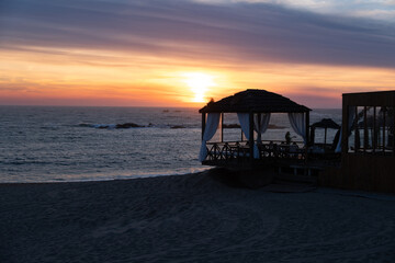 Beach bar and restaurant at sunset with beautiful colourful sunset sky, wide angle.