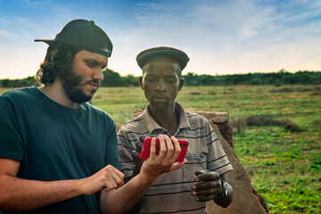 volunteer social worker at a NGO charity worker training a village african man with phone app in...
