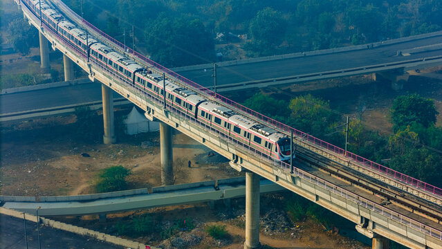 Top down view of The Delhi Metro is running on the tracks towards the Blue Line and Pink Line. Delhi Metro train. Cinematic drone shot of Metro rail in delhi.