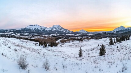Winter sunset over snow-covered mountain range. The scene features a serene landscape with snow-covered hills and evergreen trees, bathed in the warm hues of a setting sun. 
