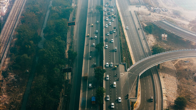 Top down cross traffic highway with cars, trucks aerial. Urban transportation at bridge road at Delhi. Cinematic cityscape of downtown freeway drone shot. Noida Freeway.