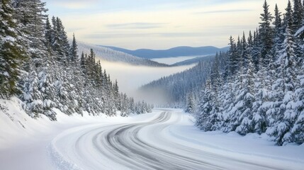 Obraz premium An icy road winding through a snow-covered forest, leading towards a misty mountain vista. The scene evokes a sense of tranquility and adventure