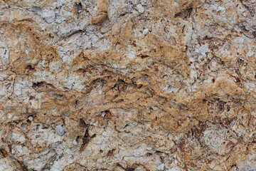 Naklejka premium Rough, natural stone texture with earthy tones, perfect for rustic backgrounds and architectural design elements. 