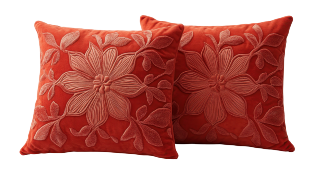 Two coral-toned velvet throw pillows with embossed floral designs; a light peach floral pattern stands out against the darker background
