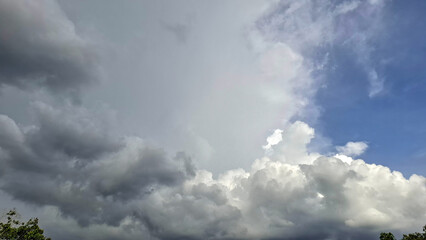A stunning landscape photo of cumulonimbus clouds forming in the sky, showing the dynamic transition between dark storm clouds and clear blue atmosphere.
