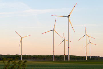 Wind turbines during sunset. Beautiful landscape with a wind power plant in Germany. Green and futuristic energy generation.