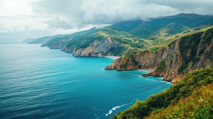 Dramatic coastline with turquoise water and rugged mountains. Lush green hills meet the deep blue ocean, showcasing a dramatic landscape.  Coastal cliffs and rocky shores are prominent features