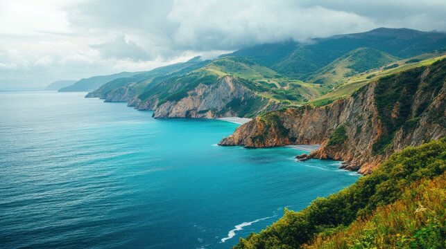 Dramatic coastline with turquoise water and rugged mountains. Lush green hills meet the deep blue ocean, showcasing a dramatic landscape.  Coastal cliffs and rocky shores are prominent features