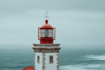 A red-topped lighthouse, white-walled, stands against a grey, turbulent sea under an overcast sky