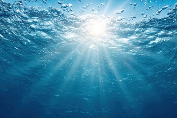 Obraz premium Underwater scene with sunbeams penetrating the surface, creating a radiant effect through the clear blue water, showing gentle waves and air bubbles