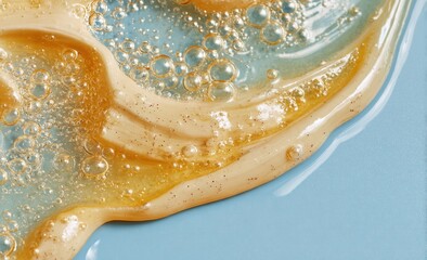 Close-up of a pale-yellow cosmetic cream with amber oil droplets and bubbles on a light-blue background, showcasing its texture and consistency