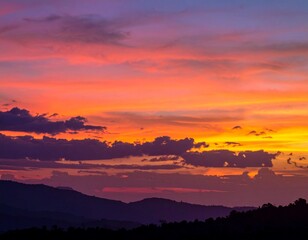 Obraz premium Vibrant Sunset Hues Over Silhouetted Mountain Ranges