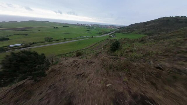 FPV Drone flying down Picota mountain in LIencres (Cantabria) on a cloudy day. At one point some rabbits cross paths as the drone descends at high speed.