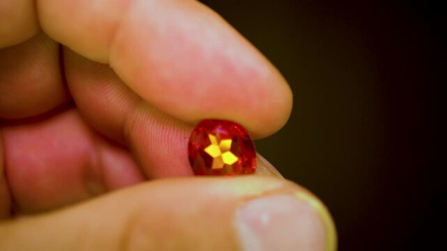 gemstones on a white table in multicolor illumination, A man's hand holds the jewels