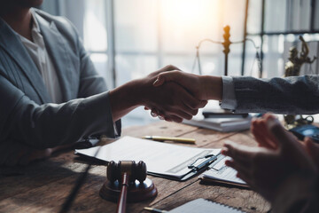 Lawyers shaking hands after signing a legal contract in their office, with legal documents and a...