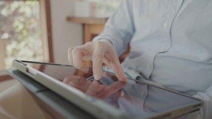 Close-up of a person using a digital tablet on their lap in natural morning light - Powered by Adobe