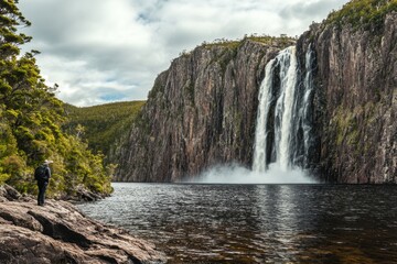 Obraz premium Majestic waterfall cascades into tranquil lake in Tasmania, Australia amidst lush greenery, Waterfall in Tasmania Australia Local landmark and travel destination