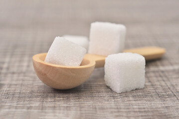 Cube sugar in woonden spoon on table background. Sugar type  are fructose, glucose, lactose. Over...