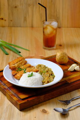 a plate of chicken katsu rice with potato curry and a glass of iced tea