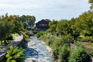 Photo of a small mountain river in a green city park. A small stream flows along the stone bed of a small stream.