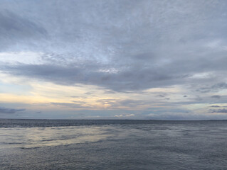 Front view of waves at empty beach and cloudy grey sky