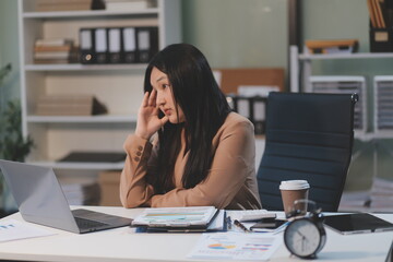 Obraz premium Asian women are stressed while working on laptop, Tired asian businesswoman with headache at office, feeling sick at work, copy space