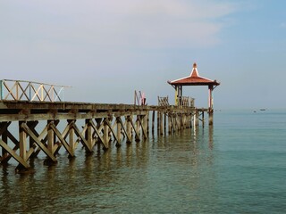 Beautiful sunrise view with wooden pier at Pantai Pasir Putih Situbondo Indonesia, tourism...
